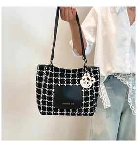 Detail of checkered tote bag with black leather front pocket and cute tiger charm