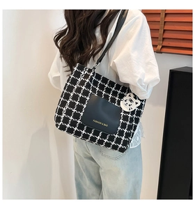 Detail of checkered tote bag with leather pocket and cute white cat pendant charm