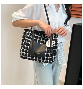 Detail of checkered tote bag featuring a leather pocket and white cat keychain