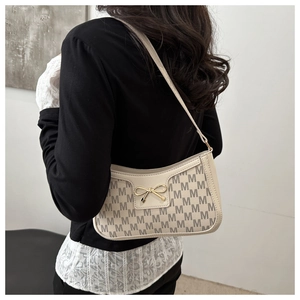 Detail of off-white crescent bag with letter pattern and golden bow hardware