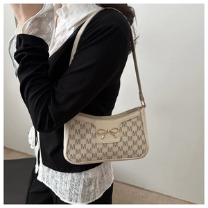 Detail of off-white crescent underarm bag featuring monogram pattern and gold bow charm