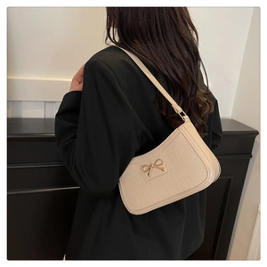 Détail d'un sac porté épaule beige à motif crocodile avec nœud doré élégant
