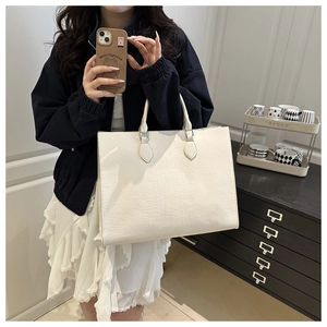 Detail of off-white crocodile texture tote bag with silver metal ring strap connectors
