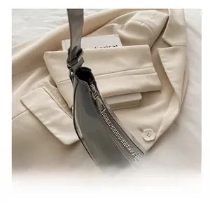 Detail of silver metal zipper on grey patent leather baguette shoulder bag
