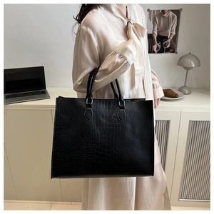 Model holding a black crocodile texture tote bag showing its large capacity and style