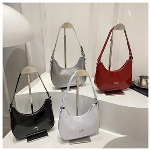 Detail view of four glossy crescent hobo bags in black, silver, red and white with bow detail