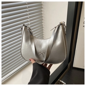 Detail of silver metallic hobo bag with delicate metal bow and adjustable shoulder strap