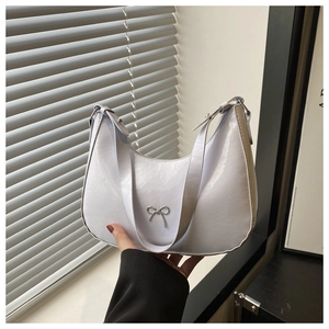 Detail of white glossy underarm bag with silver bow ornament and adjustable metal buckle