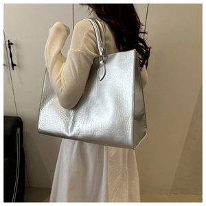 Silver crocodile texture tote bag shown on shoulder in a minimalist indoor setting