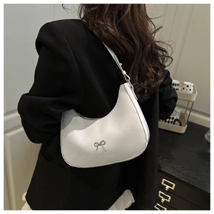 Detailed back view of a model wearing a white crescent-shaped baguette bag with silver bow