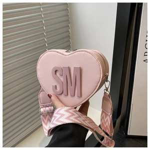 Detail of pink heart-shaped bag with textured leather and wide wave-patterned strap