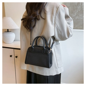 Detail of black contrast stitch handbag showing textured weave and leather paneling