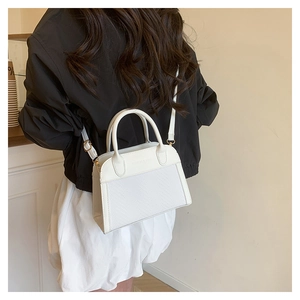 Detail shot of white trapezoid shell bag featuring woven texture and gold hardware details