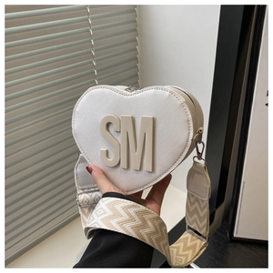 Detailed macro view of heart-shaped white crossbody bag with textured leather and 3D SM logo