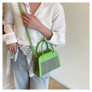 Detailed view of the green and white herringbone texture and leather strap on the tote bag