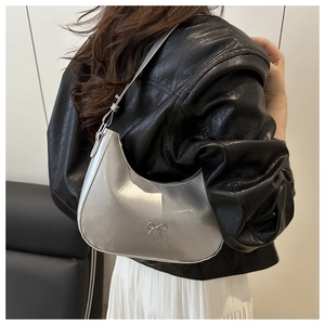 Close-up of metallic silver underarm bag with chrome bow detail and glossy finish