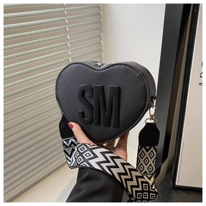 Detail of black heart-shaped leather bag with SM letters and geometric wide shoulder strap