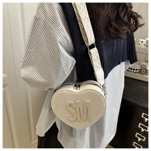Detail of cream heart bag featuring embossed SM logo and patterned wide strap