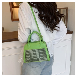 Detail of green leather and herringbone fabric handbag with adjustable shoulder strap