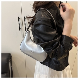 Close-up of silver crescent shoulder bag with metallic bow detail on model side view