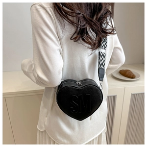Detail of a black heart-shaped crossbody bag with SM embossing and geometric wide strap