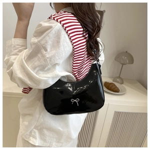 Detail of glossy black patent leather crescent bag with silver metallic bow decoration