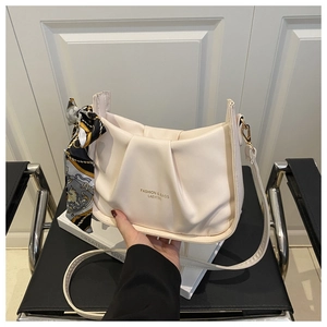 Dettaglio borsa a pieghe color crema con foulard in seta e finiture in oro lucido