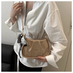 Gros plan du sac plissé beige avec un foulard à pois élégant sur la bandoulière