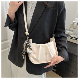 Détail du sac bandoulière plissé crème avec foulard floral et boucle en métal doré