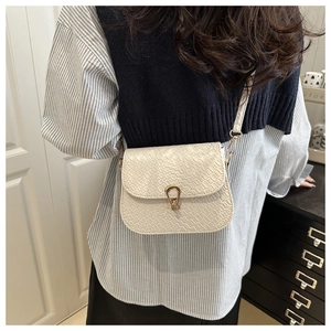 Detail of white woven texture crossbody bag with gold horseshoe buckle on model