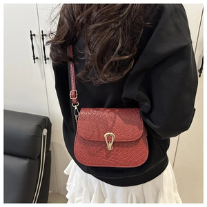 Detail of reddish-brown woven textured crossbody bag with elegant gold metal lock