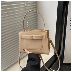 Close-up of beige Saffiano leather bag featuring a gold turn-lock and detachable strap