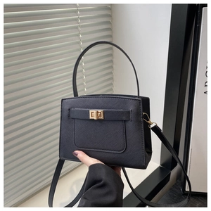 Detail of black Saffiano texture crossbody bag with gold-tone metal twist lock closure