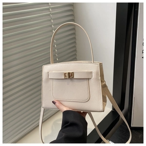 Detail of cream white leather handbag with golden twist lock and natural light shadows