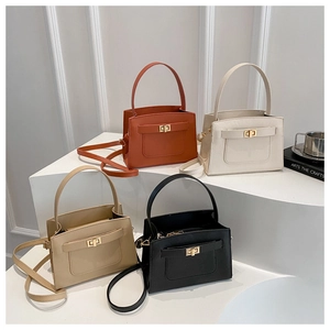 Detail view of structured handbags in brown, white, khaki, and black with gold turn-lock