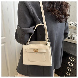 Detail of a creamy white crossbody bag showing the chic gold twist lock and fine grain leather