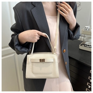 Close-up of beige Saffiano leather texture with gold turn-lock buckle and handbag handle
