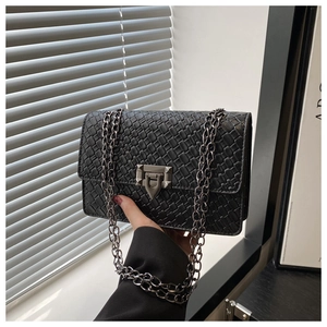 Detail of black woven rectangular crossbody bag with triangle rivet buckle and silver chain