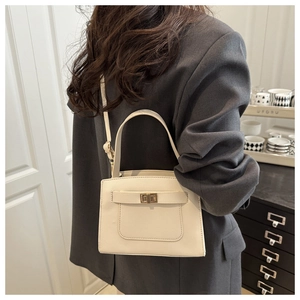 Detail of cream white faux leather tote with golden twist lock on casual blazer