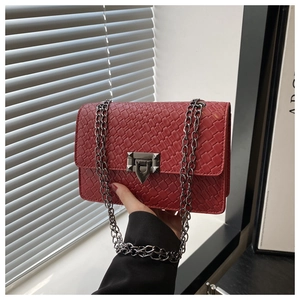 Detail of red woven leather texture and silver geometric clasp on a luxury chain bag