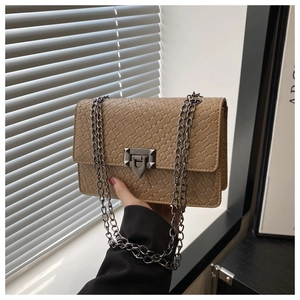 Macro shot of khaki woven texture and metallic chain strap on a small square shoulder bag