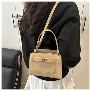 Detailed back view of a beige crossbody bag with gold turn-lock on a fashion model