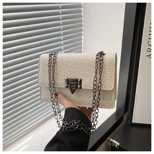 Detail view of cream woven shoulder bag with dark grey metal twist lock and chain strap
