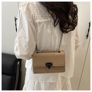 Detailed back view of a woman wearing a beige stone-patterned chain crossbody bag