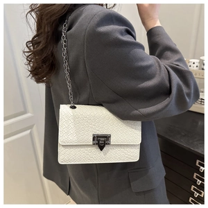 Detail of white woven texture square bag with silver chain strap shown on shoulder