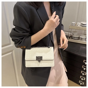 Close-up of a white woven texture square bag with dark metal chain strap and clasp