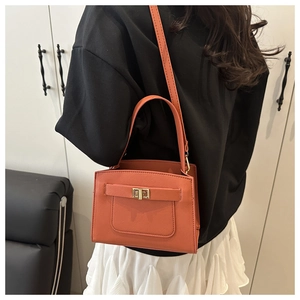 Detail of orange crossgrain faux leather handbag featuring a golden rectangular twist lock
