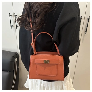 Orange red Saffiano leather handbag shown on model featuring a golden twist-lock closure