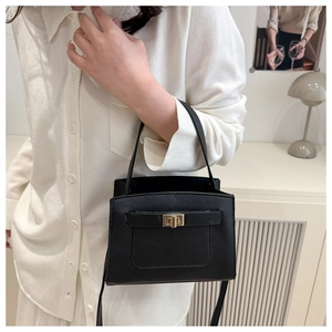 Detail shot of black Saffiano leather bag with a gold turn-lock and crosshatch texture