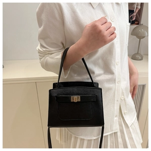 Detail view of black lychee texture handbag with gold twist lock and crossbody strap